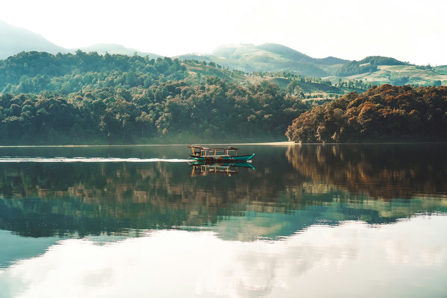 Turquoise boat with cabin on a calm lake.