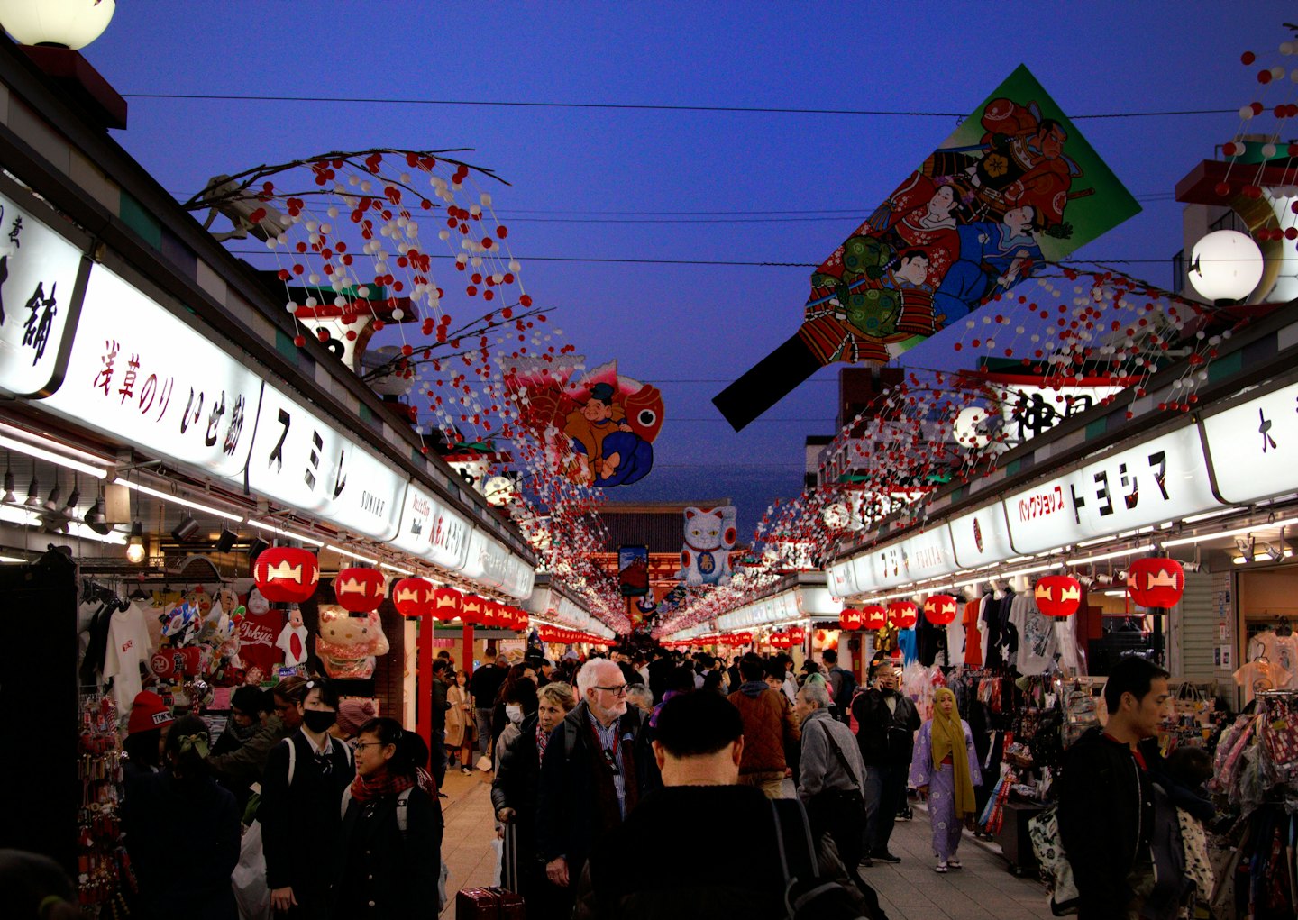 Shoppers browse stalls under lanterns at a busy night market.